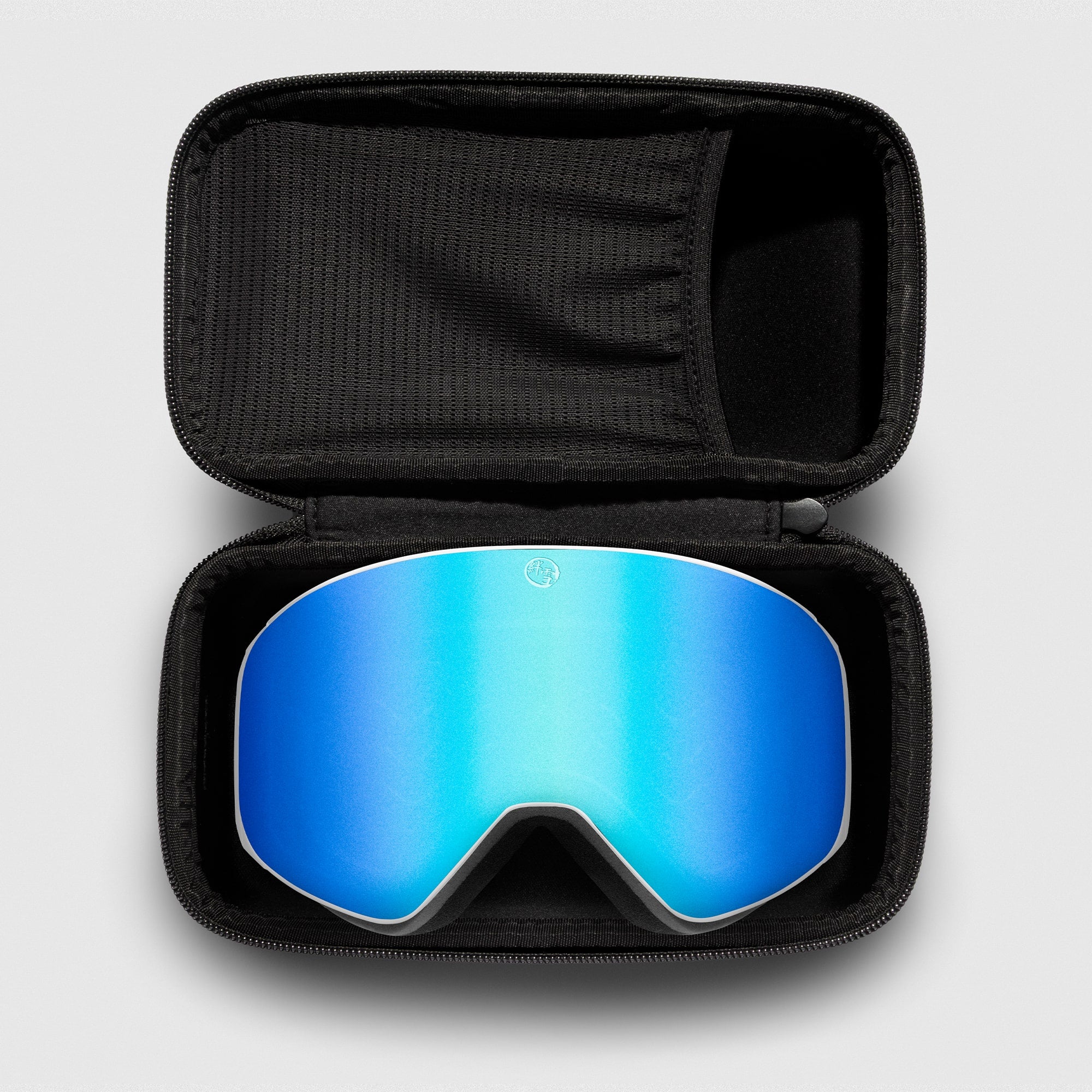 Blue reflective ski goggles, with white frame in a black case on a light gray background