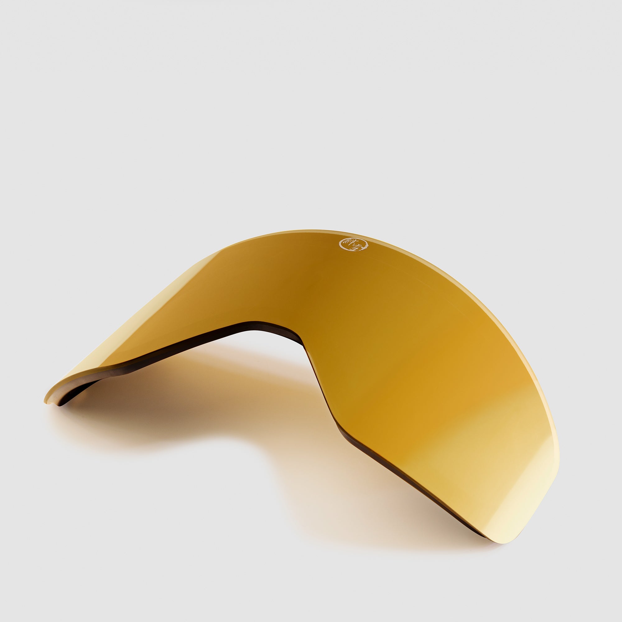 Angled gold ski goggles lens on a light gray background