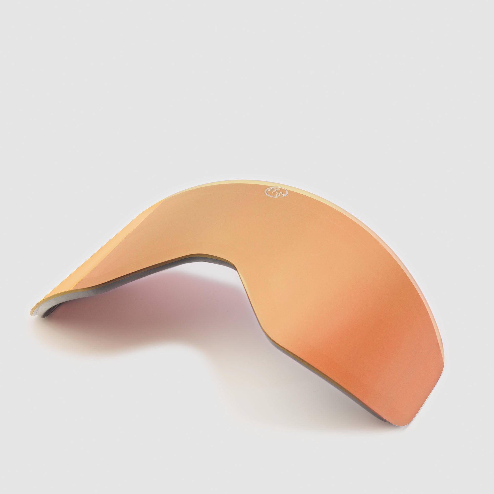 Angled rose gold ski goggles lens on a light gray background