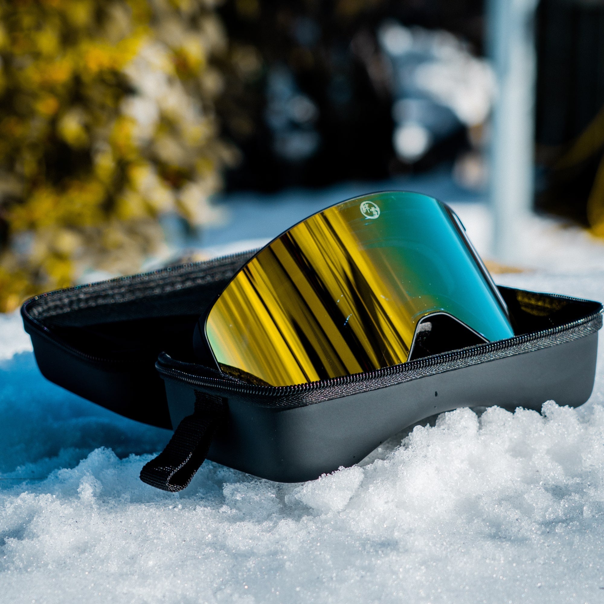 Sunglasses with reflective lenses in a black case on snow