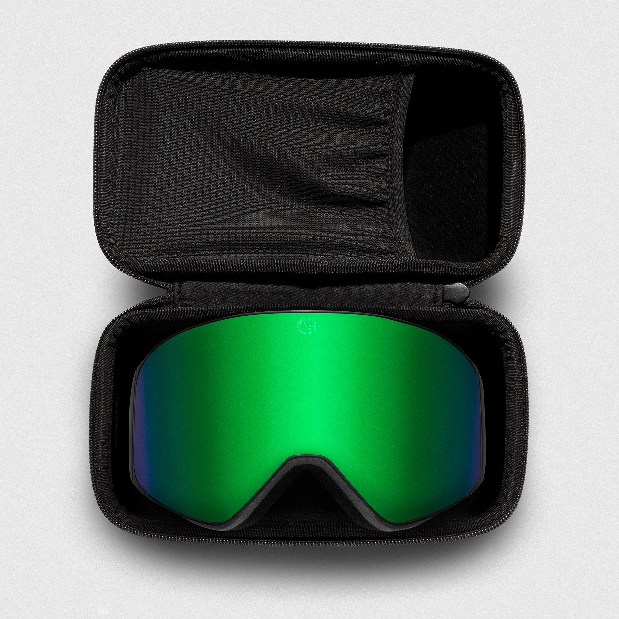 Green reflective ski goggles, with black frame in a black case on a light gray background