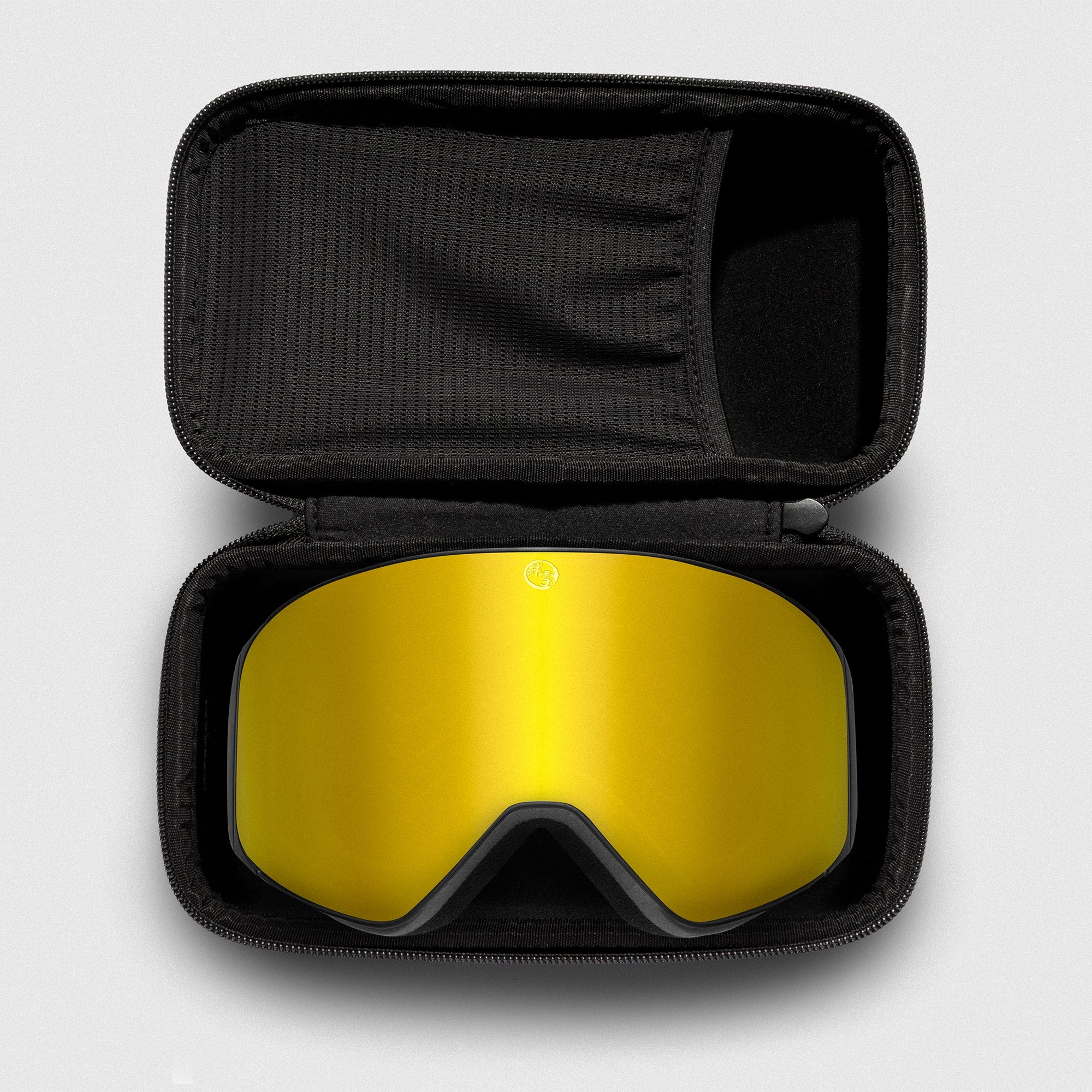 Gold reflective ski goggles, with black frame in a black case on a light gray background