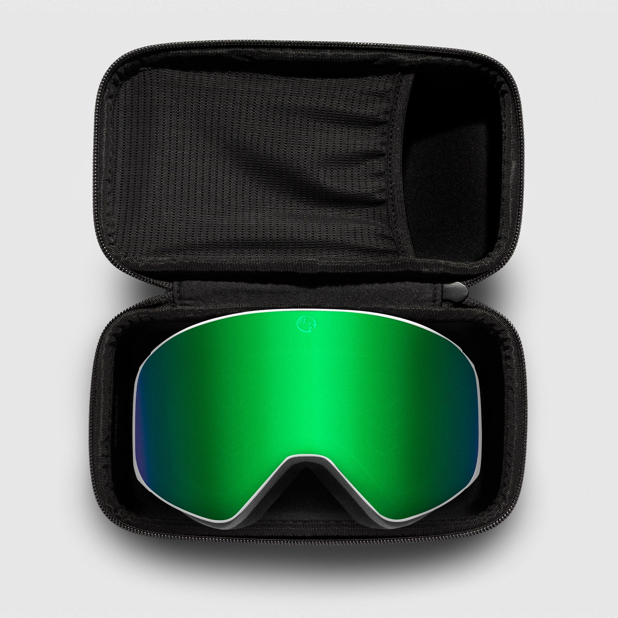 Green reflective ski goggles, with white frame in a black case on a light gray background