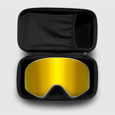 Gold reflective ski goggles, with white frame in a black case on a light gray background