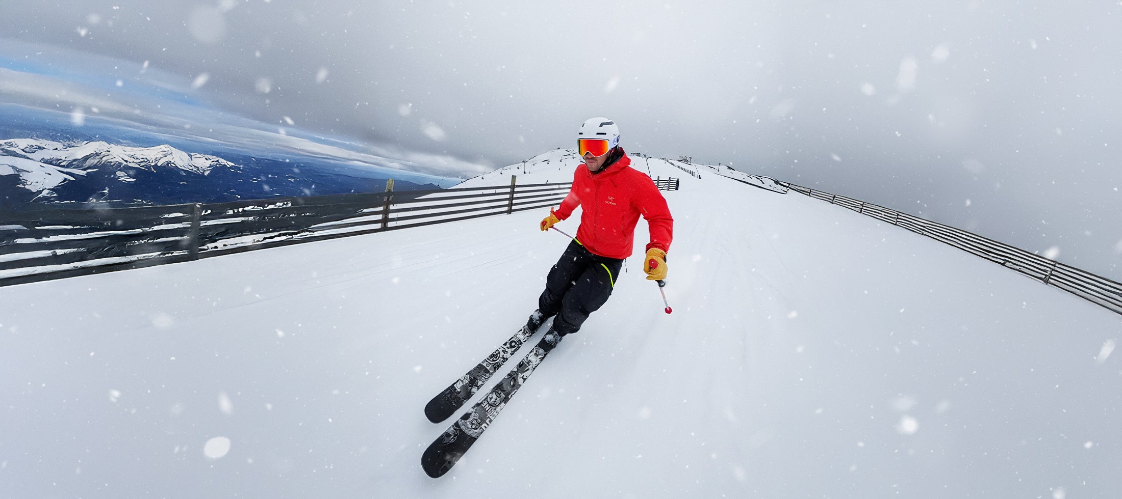 Wide-angle view of skier descending a snow-covered slope in alpine conditions, showcasing speed, control, and visibility.