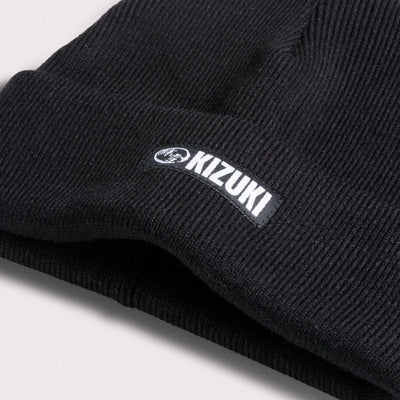 Close up shot of a Black beanie with Kizuki logo on a light gray background