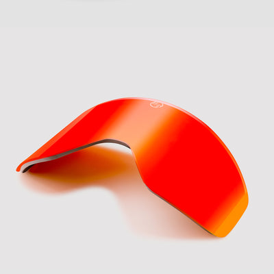 Angled red ski goggles lens on a light gray background