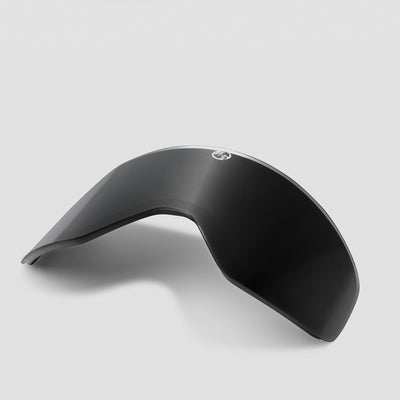 Angled black ski goggles lens on a light gray background