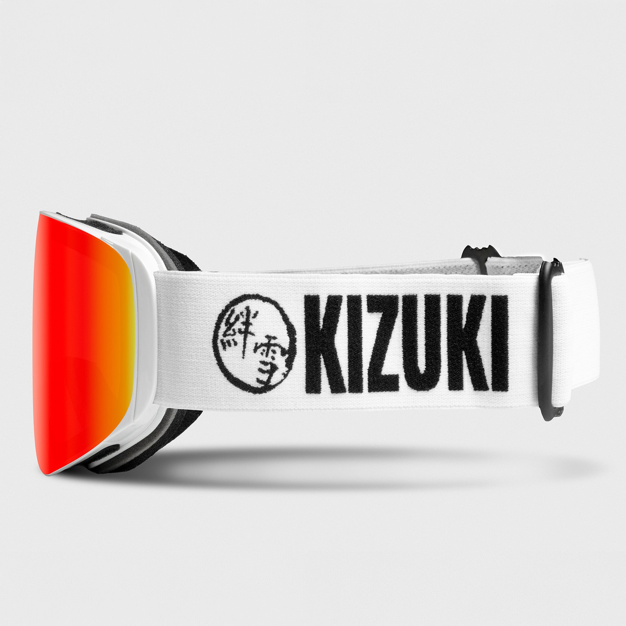 Ski goggles with red lenses and white strap displaying 'KIZUKI' on a light gray background