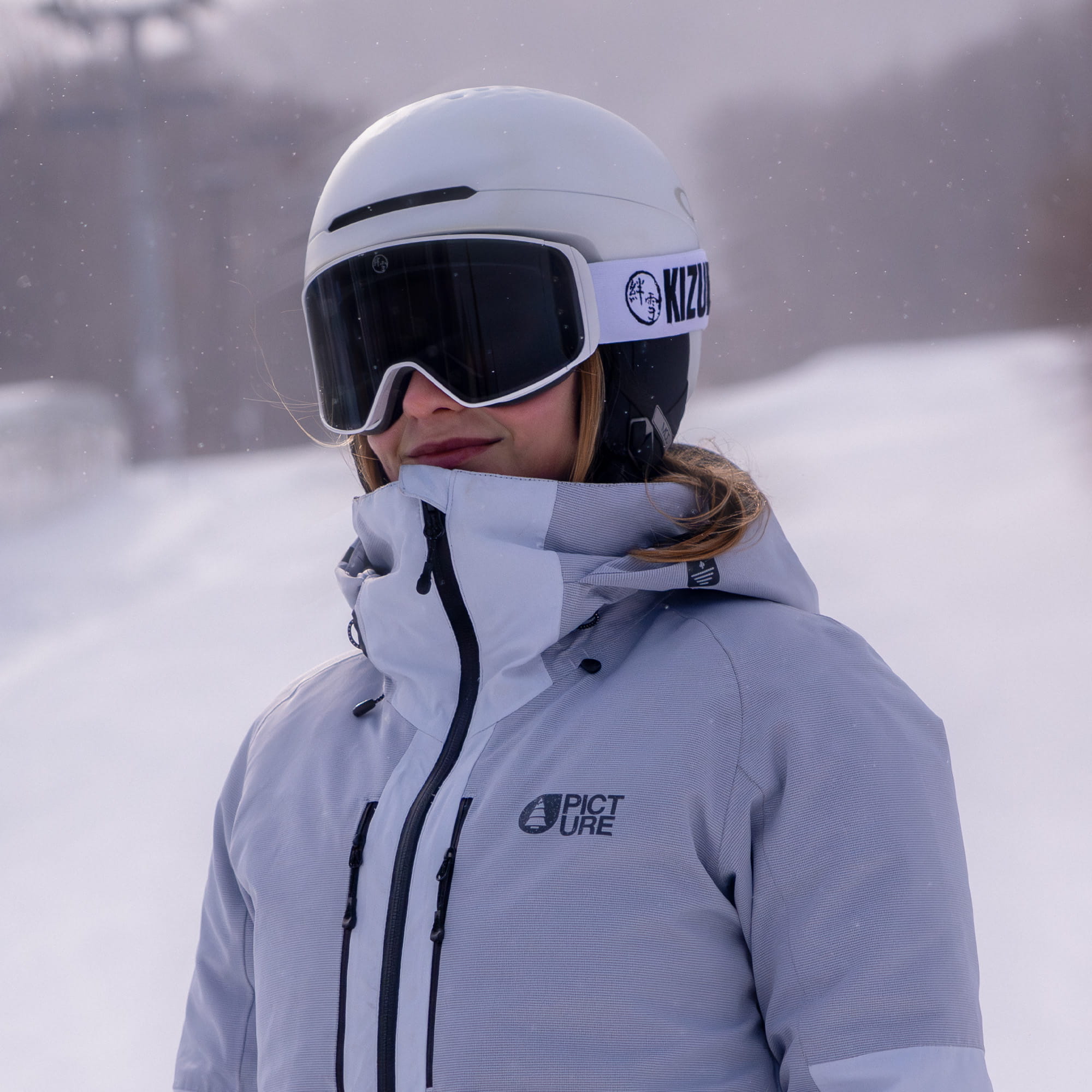 Person wearing a helmet and black goggles with a snowy background