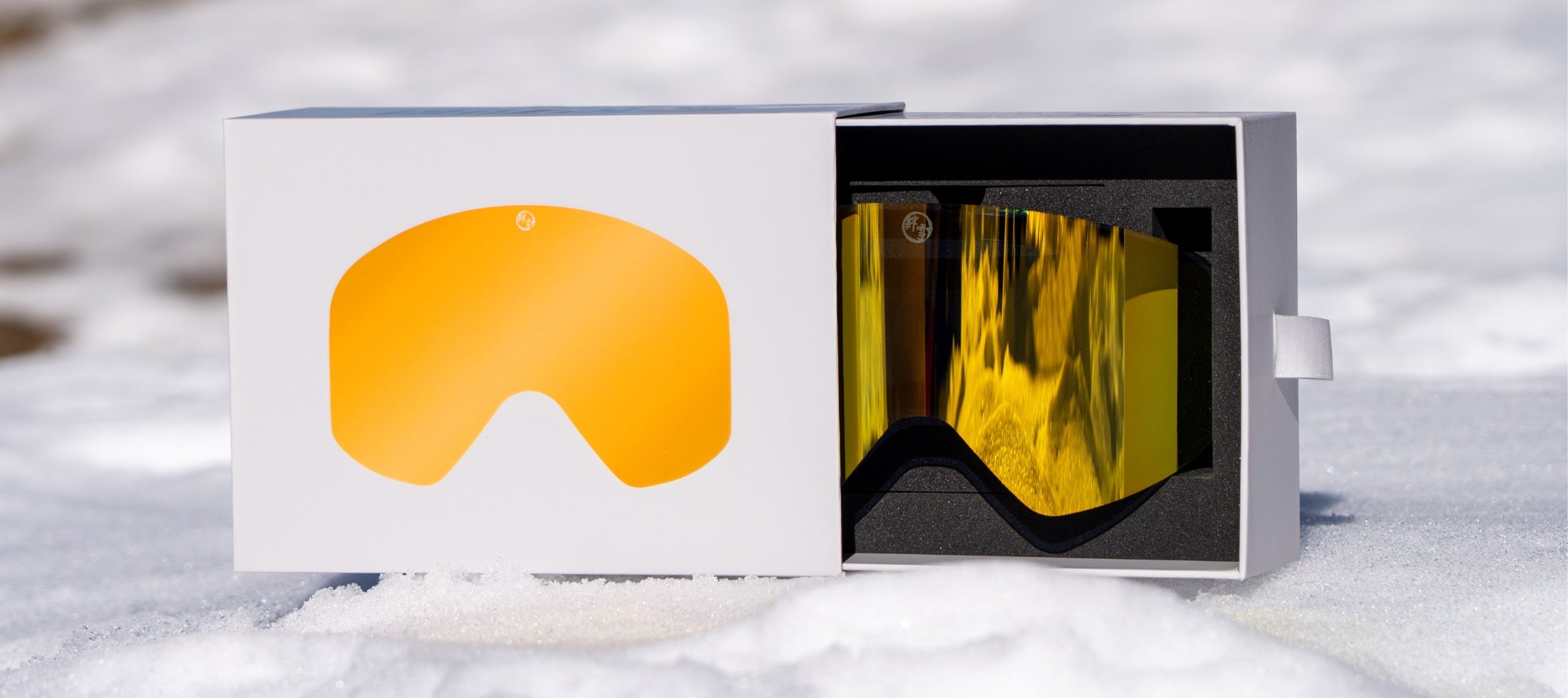 KIZUKI ski goggles with Summit Gold mirrored lens in premium packaging, showcased on snow with box and lens cover.